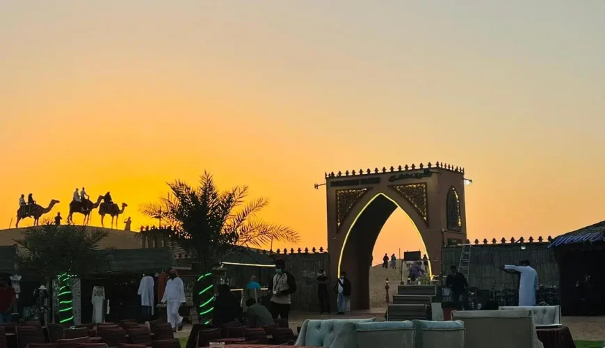 Desert Safari Outfit Ideas A man and woman wearing breathable desert safari outfits, standing on sand dunes under the sun in Dubai.